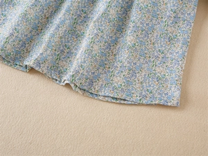 Gros plan sur un tissu floral léger aux fleurs bleues et couture d'ourlet soignée