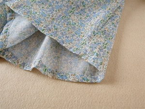 Gros plan détaillé du tissu floral bleu avec couture d'ourlet précise pour robe fille