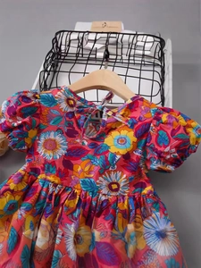 Girls floral cotton dress with puff sleeves and colorful sunflower print on a wooden hanger