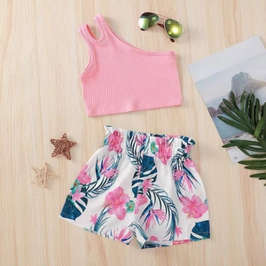 Flat lay of girl's pink one-shoulder ribbed top and hibiscus floral print shorts set