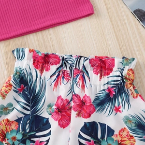 Detail of pink ribbed knit tank top and tropical hibiscus print shorts on wooden background