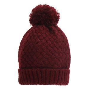 Close-up of dark red honeycomb knit beanie with fluffy pompom and ribbed cuff detail