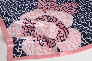 Close-up of printed silk-like scarf featuring abstract letter patterns and satin texture