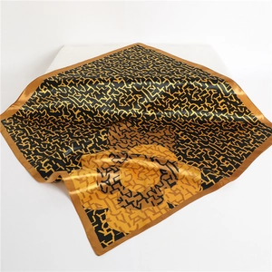 Detailed view of large satin square scarf with black gold floral and letter pattern