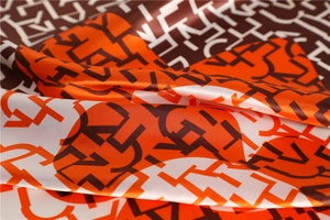 Close-up of geometric letter pattern on smooth satin scarf with elegant orange color block