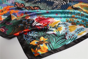 Detailed macro view of tropical jungle floral print silk scarf with black satin border