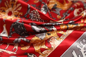 Vue détaillée d'un foulard en soie rouge avec motifs léopard, oiseaux et fleurs