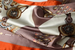 Close-up of luxury satin square scarf with equestrian chain print and smooth texture