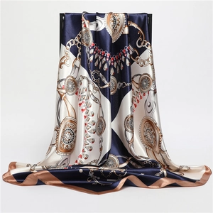 Detailed drape of a satin silk scarf with vintage gold chains and geometric patterns
