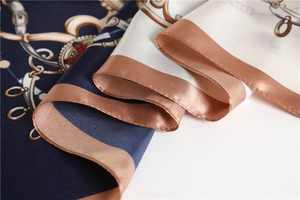 Macro view of satin scarf showing classic chain and horsebit print with machine edge