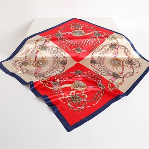 Detail of luxury satin square scarf featuring red and champagne color blocks with gold chains