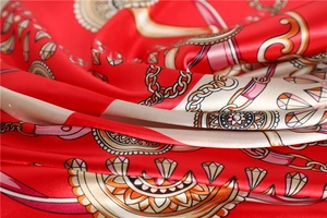 Macro shot showing glossy silk texture with vintage chain and gem print on red scarf
