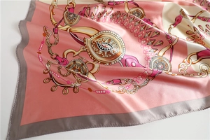 Detail of silk-satin scarf with pink and beige equestrian chain pattern and grey border