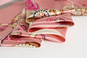 Close-up of pink silk satin scarf featuring chain patterns and smooth elegant texture