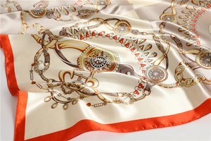 Detailed close-up of premium satin silk square scarf with golden chain print and orange border