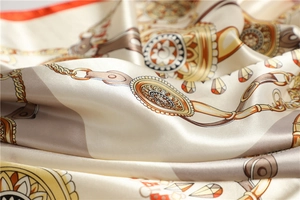 Macro shot of satin silk scarf detailing vintage chain patterns and jewel prints