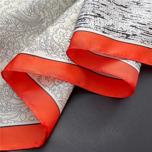 Close-up of vintage paisley silk scarf featuring orange borders and soft twill texture