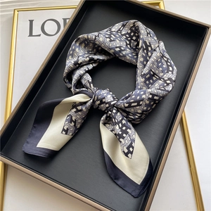 Close-up of elegant silk square scarf with geometric letter patterns on luxury tray