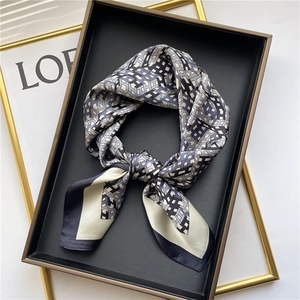Detailed view of geometric pattern silk scarf in navy and grey on a black tray