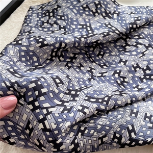 Close-up of silk-textured scarf showing intricate blue and black H-letter pattern