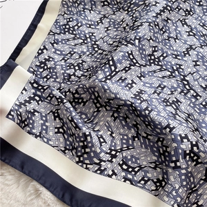 Macro shot of silk-like scarf with blue geometric H patterns on plush background