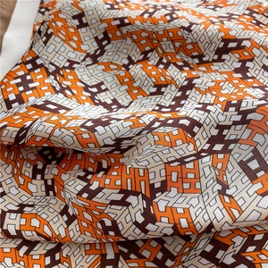 Close-up of silk-textured fabric with geometric H pattern in orange and brown