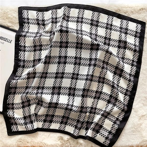 Classic black and white houndstooth square scarf with a satin finish on a plush carpet
