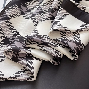 Detail of black and white checkered silk scarf texture with fine stitching on satin fabric