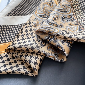 Detail of silk-like scarf with gold paisley, houndstooth patterns and elegant drapes