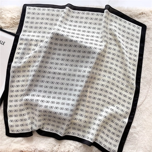 Close-up of elegant silk-feel square scarf with black butterfly patterns and wide borders