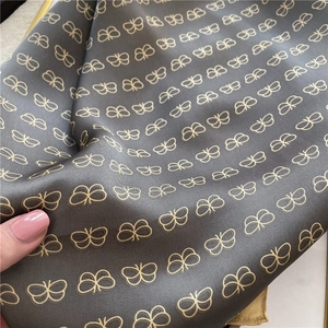 Detail shot of elegant butterfly print on silky dark fabric with soft draping folds