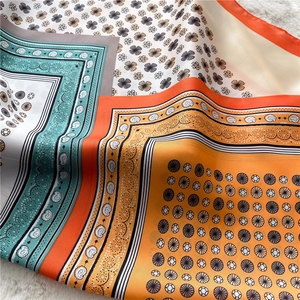 Detail of vibrant paisley and sunflower patterns on a glossy faux silk square scarf