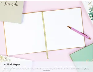 Flat lay of open linen guest book with premium blank white pages and gold silk bookmark