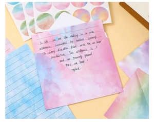 Macro shot of watercolor gradient envelopes and lined stationery with decorative stickers