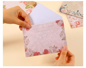 Close-up of vintage floral envelope with red rose patterns and matching letter paper