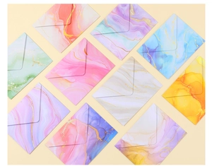 Flat lay of watercolor marble envelopes with gold glitter veins and ink gradient