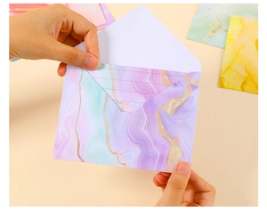 Detailed view of hand holding a purple marble texture envelope with lined writing paper