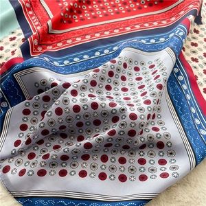 Macro detail of silk square scarf featuring paisley patterns and vibrant color blocking