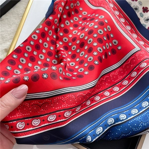 Detail of soft silk-like square scarf with red polka dots and blue paisley patterns