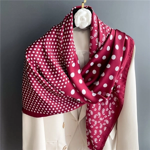 Close-up of wine red silk scarf with paisley and polka dot pattern on a white blazer