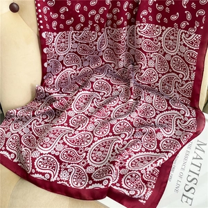 Artistic drape of burgundy paisley satin scarf over a beige chair with art book