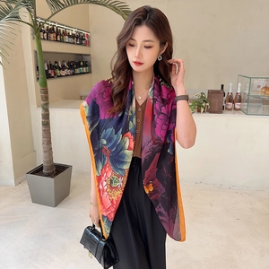 Detail of silk satin scarf showing vibrant floral peony patterns and butterfly design