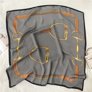 Detail of luxury silk square scarf with houndstooth print and equestrian chain patterns