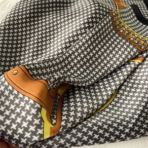 Close-up of silky houndstooth scarf with luxury gold chain and leather belt pattern