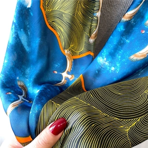 Detail of silk scarf showing crane embroidery and golden wave patterns on star blue fabric