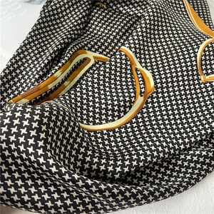 Detail of luxury silk scarf with houndstooth pattern and equestrian chain design
