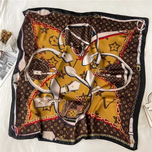 Detailed view of printed silk square scarf with golden chain patterns and luxury motifs