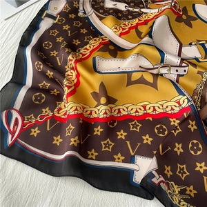 Detailed close-up showing silky fabric texture with vintage chain and logo patterns