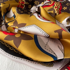 Detailed view of yellow and black silk scarf with luxury monogram and chain prints
