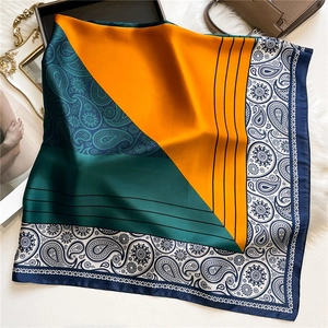 Detailed satin texture of orange and navy blue silk scarf with classic paisley patterns
